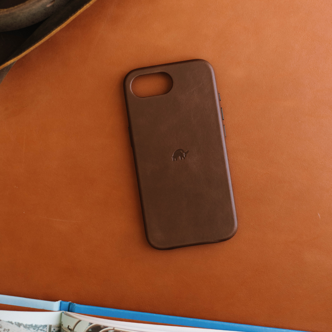 Brown leather phone case with small embossed elephant logo on tan leather background