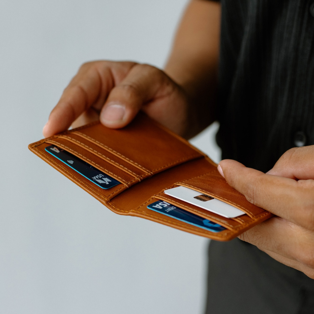Brown leather wallet held open showing a white chip card and a blue VISA card in card slots