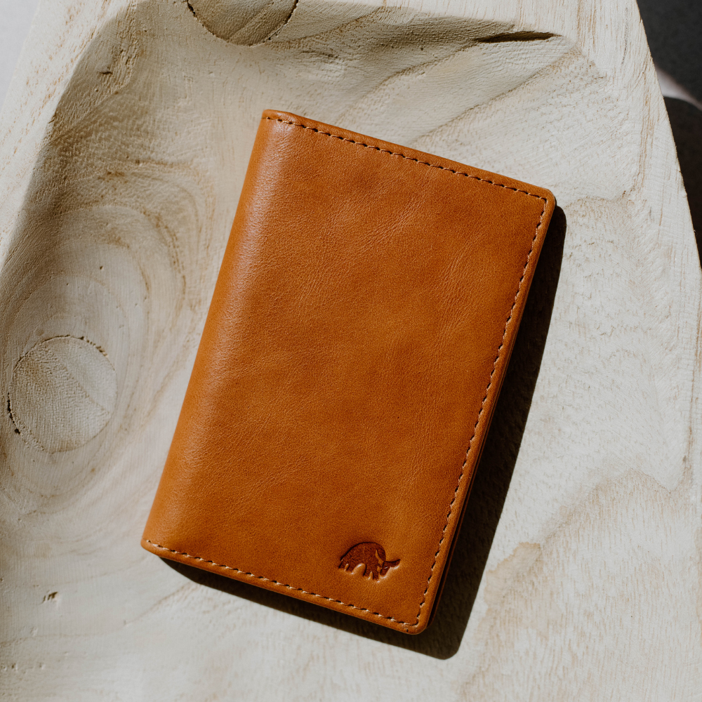 Sienna leather minimalist phone case resting on a brown leather jacket