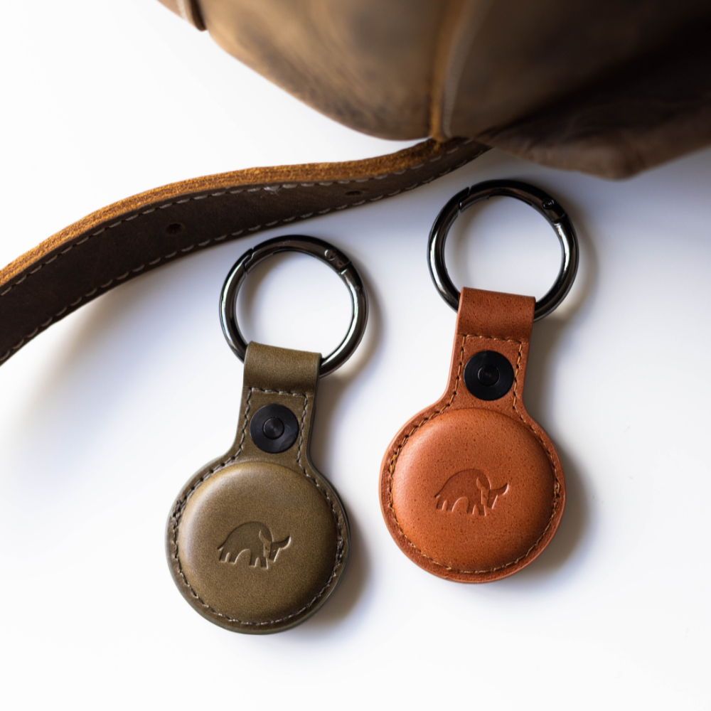 Two BullTags for AirTag in olive green and brown leather, attached to a keyring.