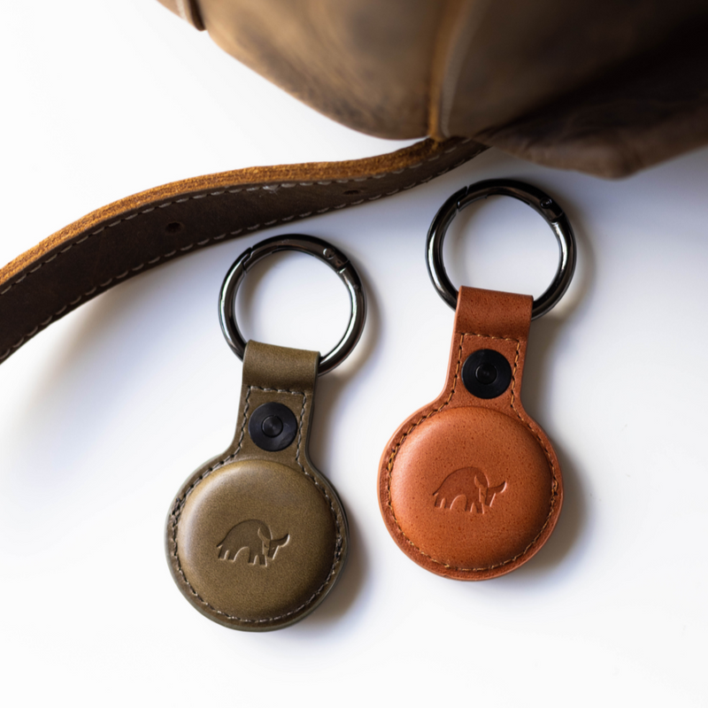 Two BullTags for AirTag in olive green and brown leather, attached to a keyring.