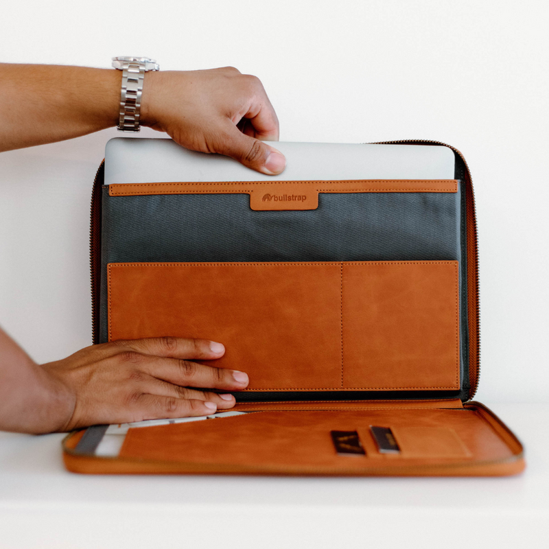 Front-open view of Sienna leather MacBook sleeve showing padded laptop pocket, card slots, and full-zip closure on white background