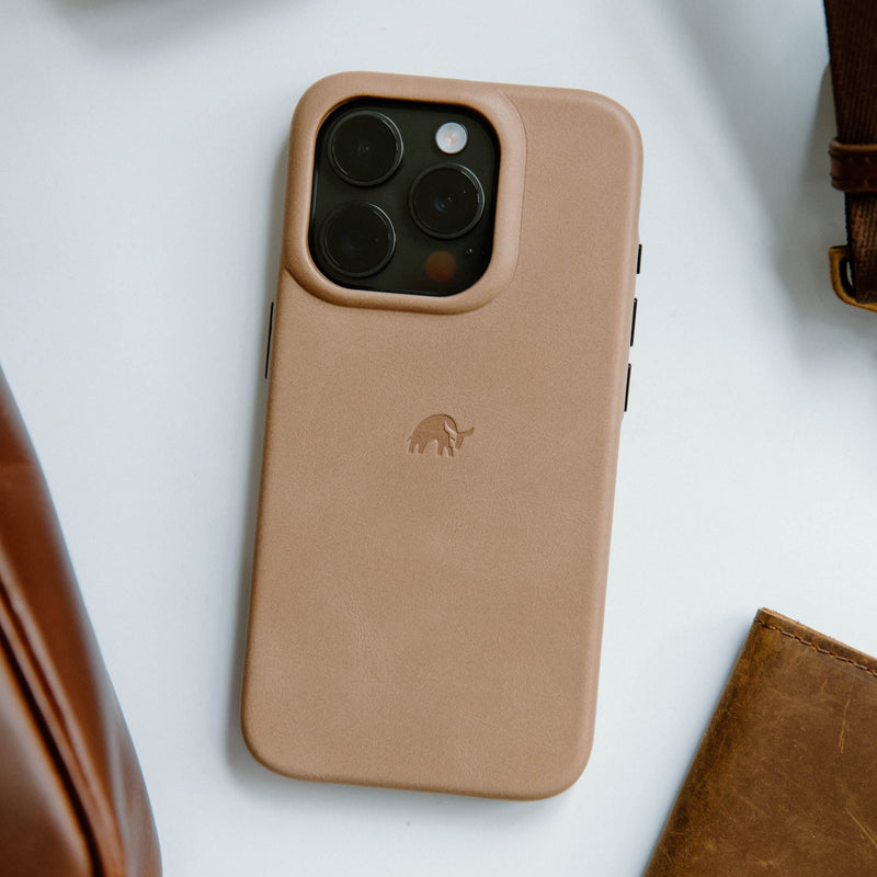 Tan leather smartphone case with raised triple-camera cutout and embossed elephant logo on white surface.