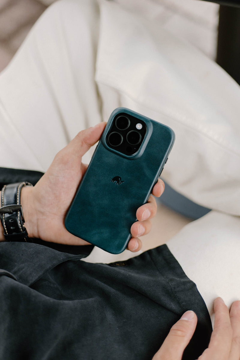 A person holding a Bullstrap iPhone case in teal color.