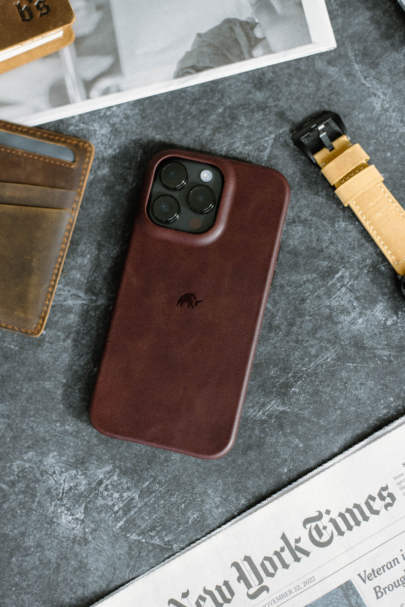 Rear of Minimalist Case, Bourbon showing raised camera cutout and embossed logo on dark tabletop