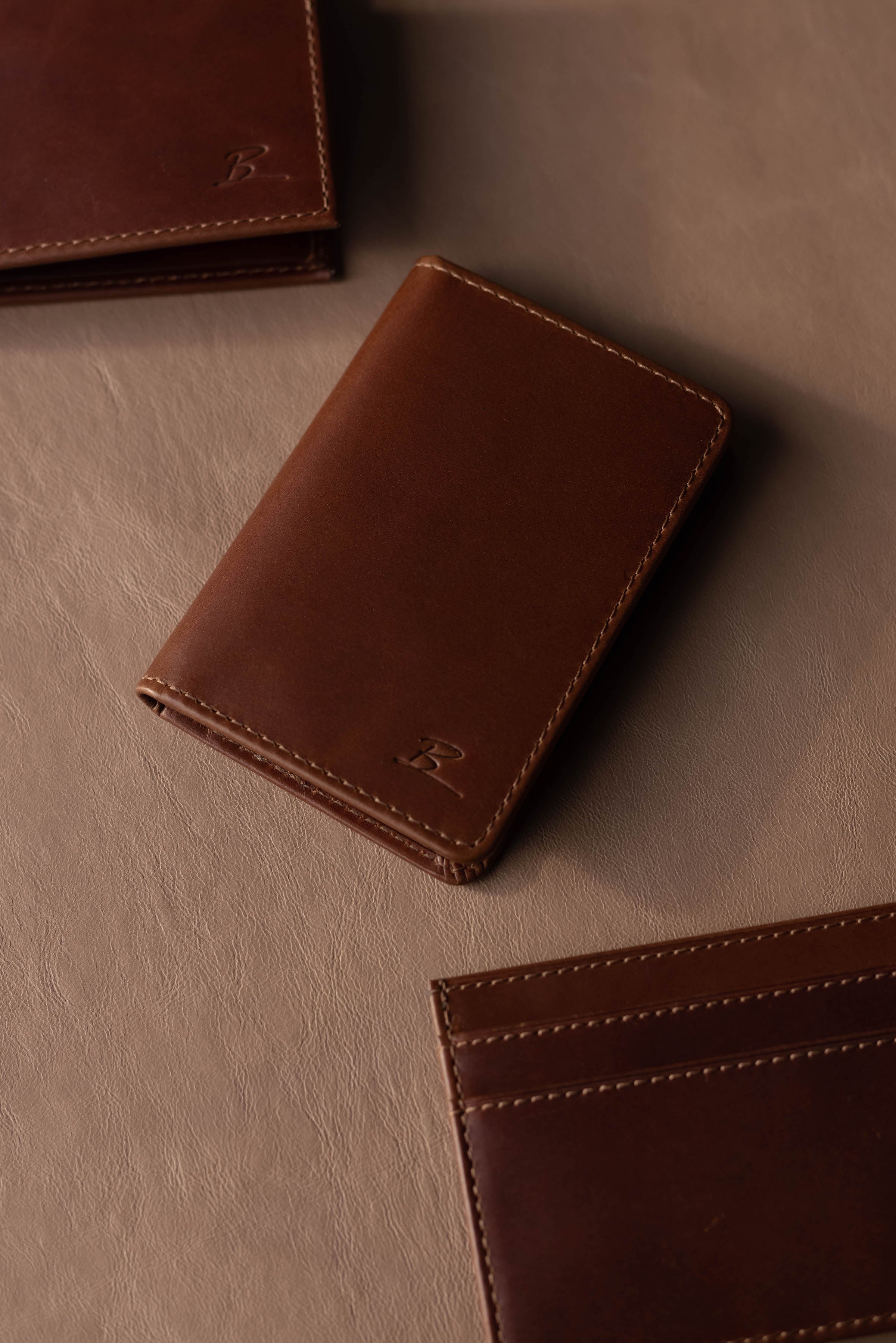 Brown leather wallet and cardholder on tan leather surface, both with an embossed B logo.