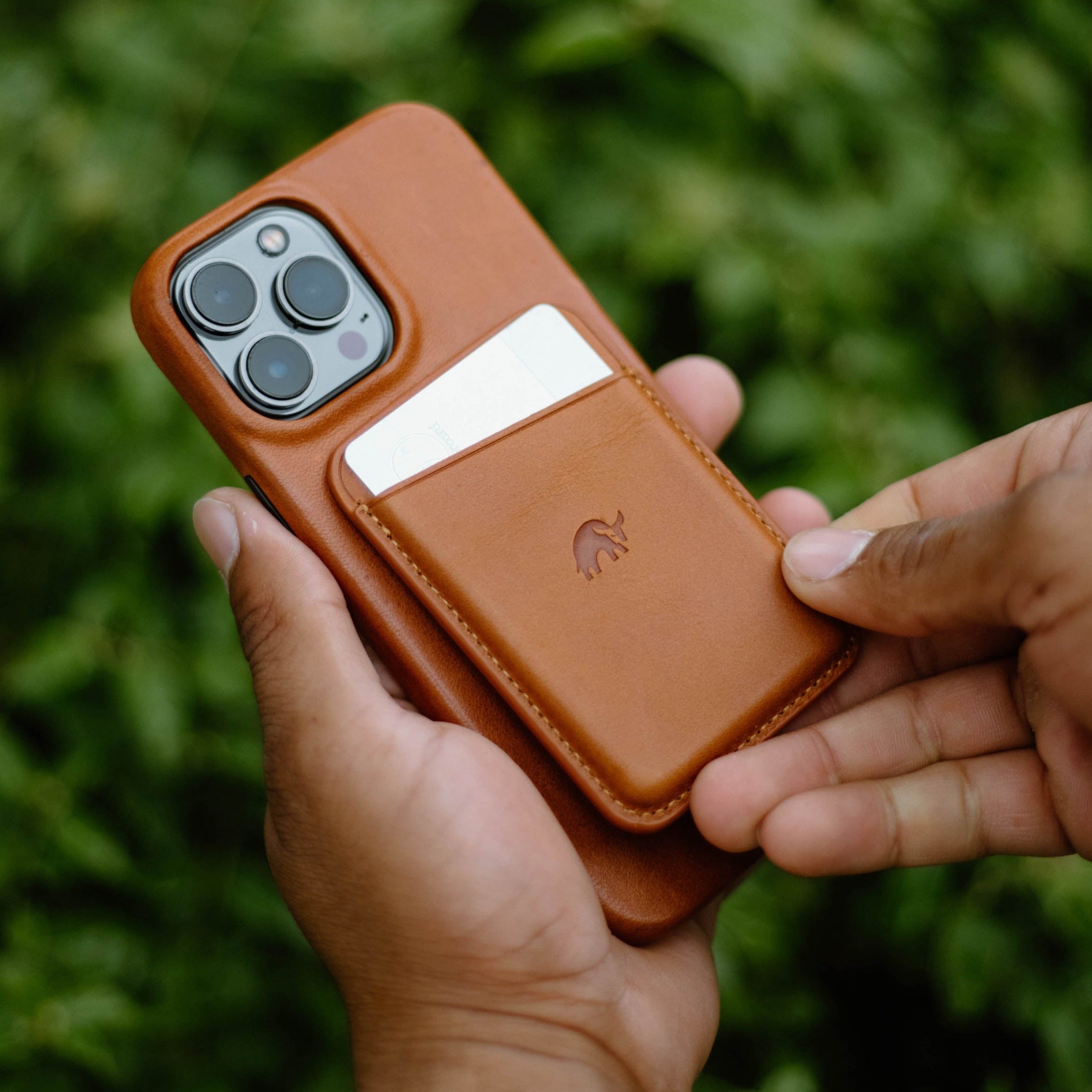 A person holding a leather magnetic wallet with a phone and card visible.
