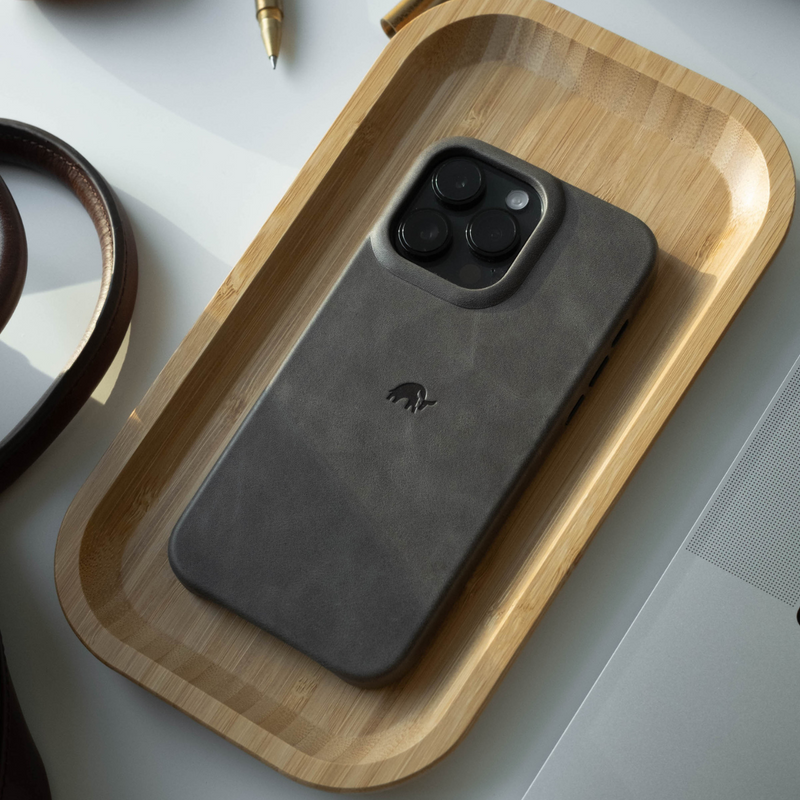 The Minimalist Case in slate color on a wooden tray, showing camera cutouts and logo.