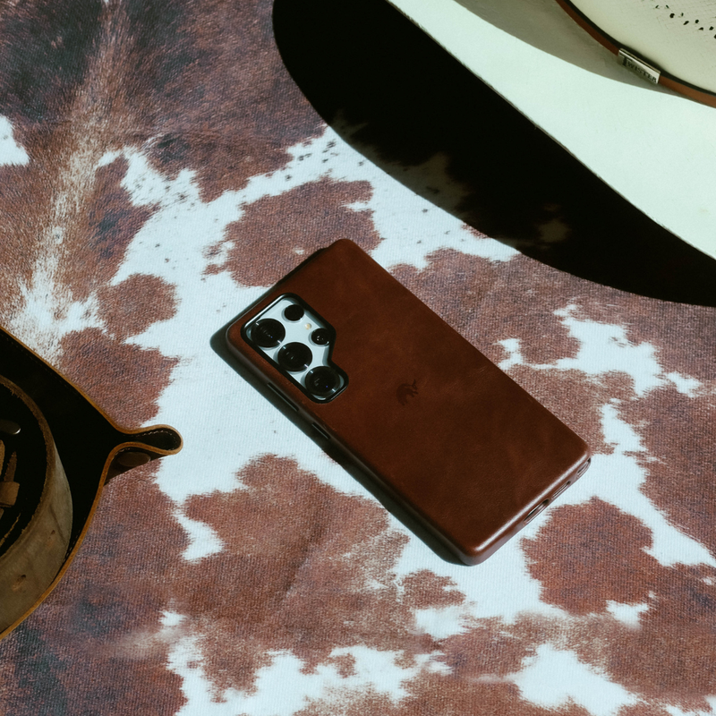 Angled view of Samsung Galaxy S25 Ultra Terra case showing brown leather, camera cutout and embossed logo on cowhide