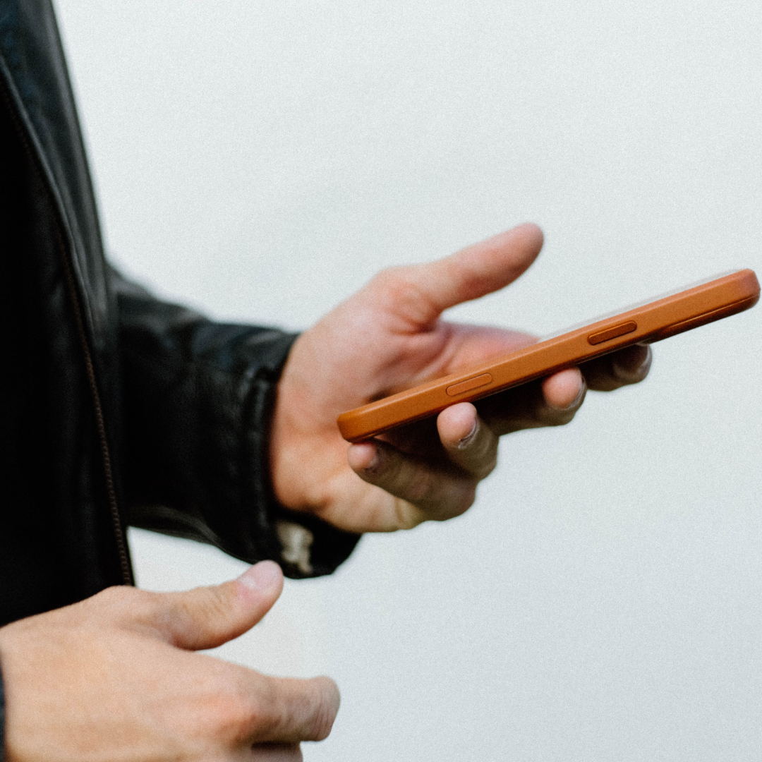 Hands holding a phone in a sienna Flex Case, showing the side buttons.