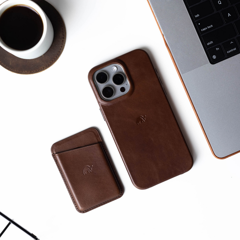 Brown leather iPhone case and cardholder on a desk with a laptop and coffee cup