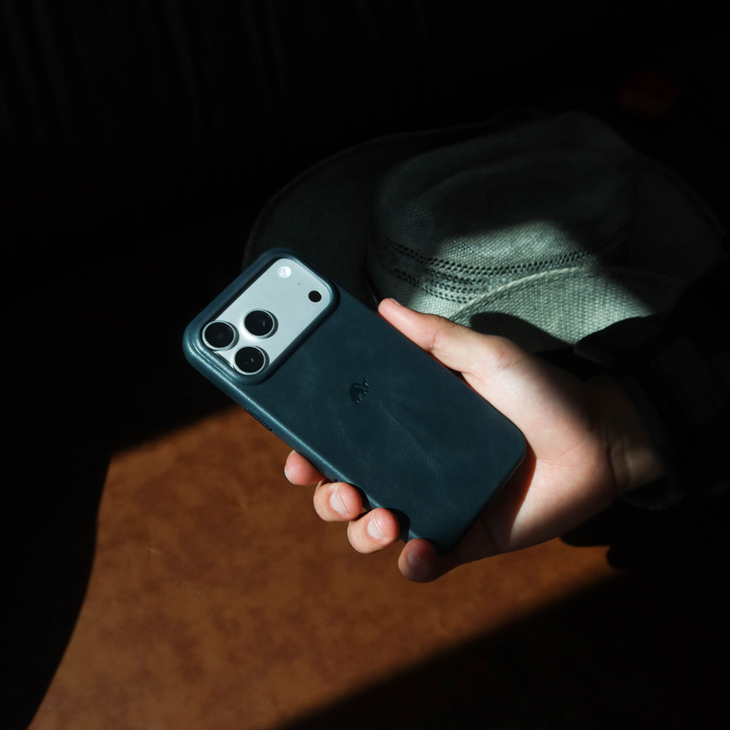 Angled rear view of Contemporary Plateau Case in Ocean leather showing camera cutout, held in hand against dark backdrop