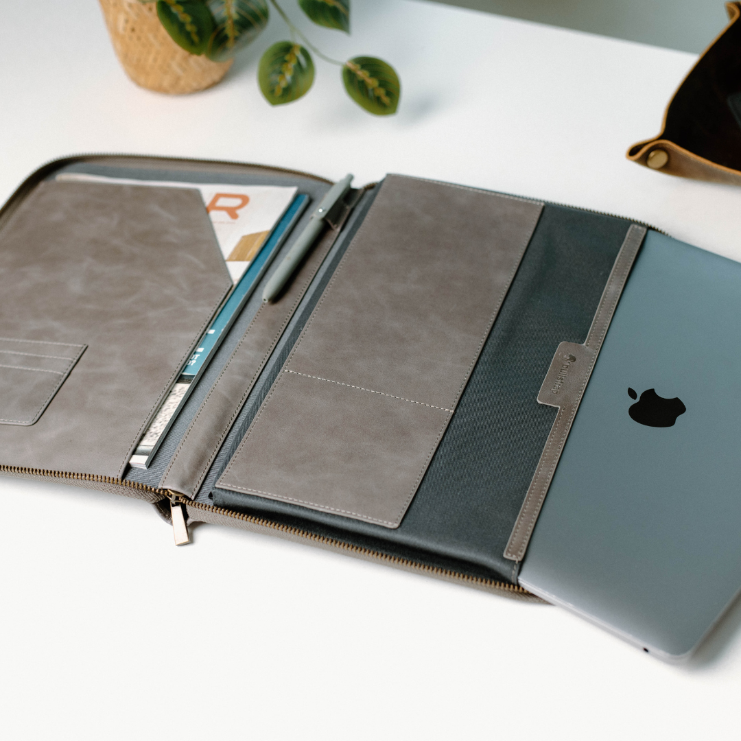 Open leather MacBook sleeve showing interior compartments and a MacBook inside.