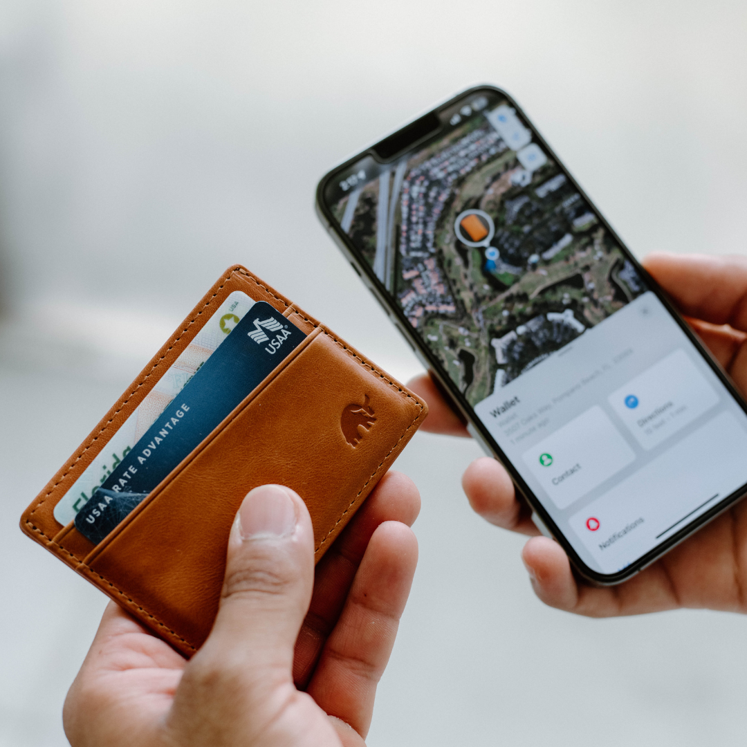 Sienna leather card holder in hand with USAA RATE ADVANTAGE card visible beside phone showing Wallet, Contact, Notifications.