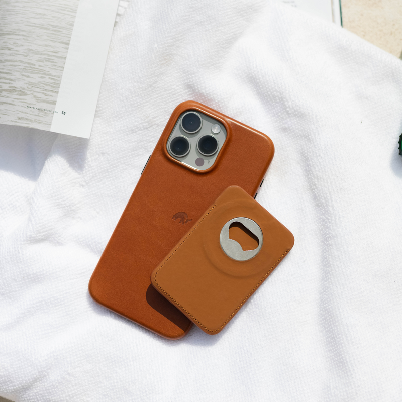 Top-down view of Sienna MagSafe Popper wallet and matching leather iPhone case showcasing stainless steel bottle opener on a white towel
