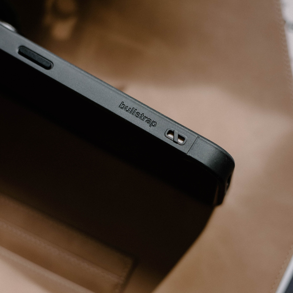 Close-up of a black phone case edge embossed with the word 'bullstrap' and a small strap hole