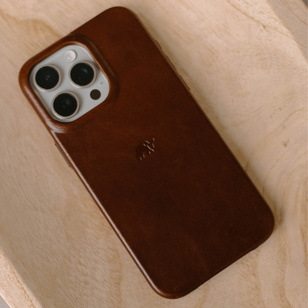 Brown leather iPhone case with camera cutouts on a wooden surface