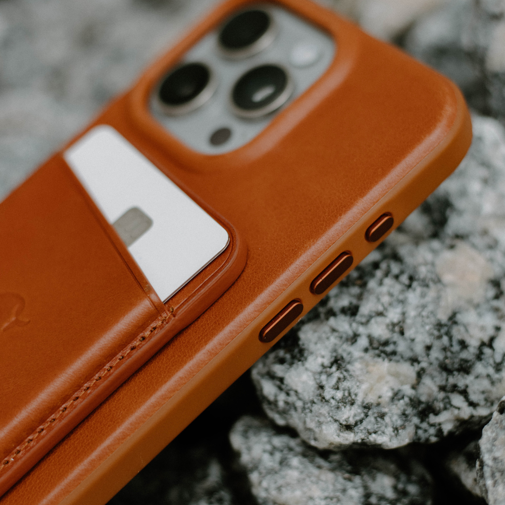Close-up of the Flex Case in Sienna color with a card slot, resting on rocky surface.