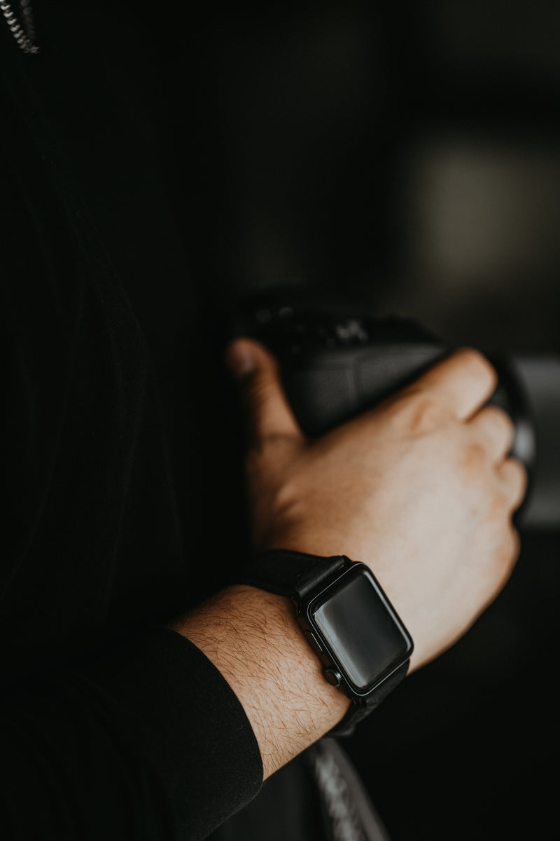 A person holding a camera with a smartwatch on their wrist.