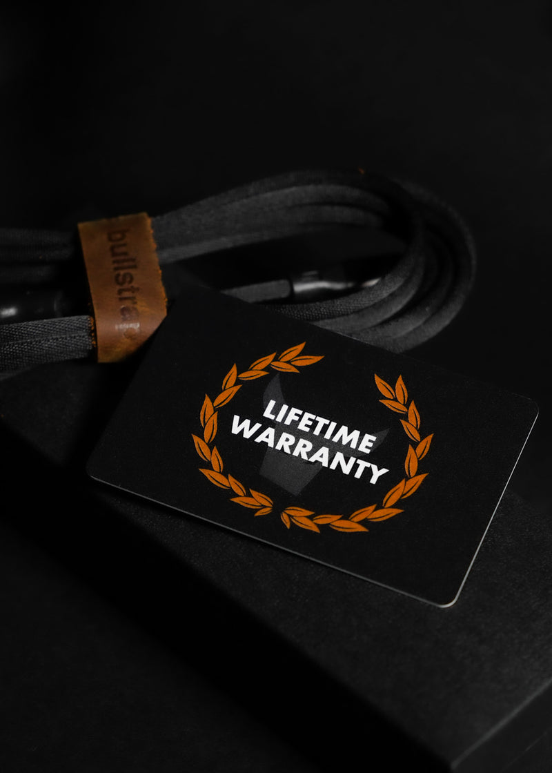 Black warranty card reading "LIFETIME WARRANTY" with orange laurel wreath, resting on a coiled black cable.