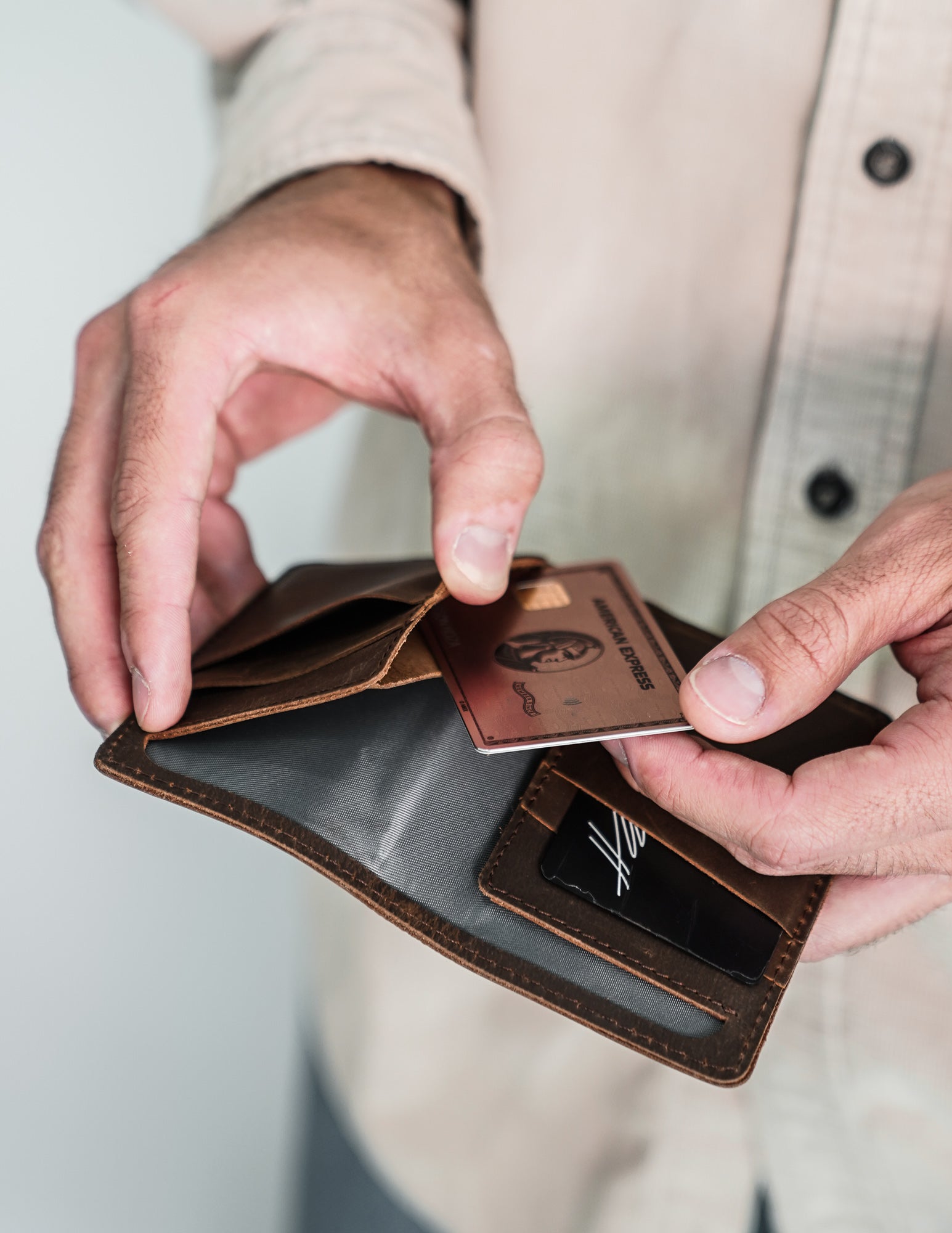 A person holding a wallet with cards being inserted, showcasing its interior.