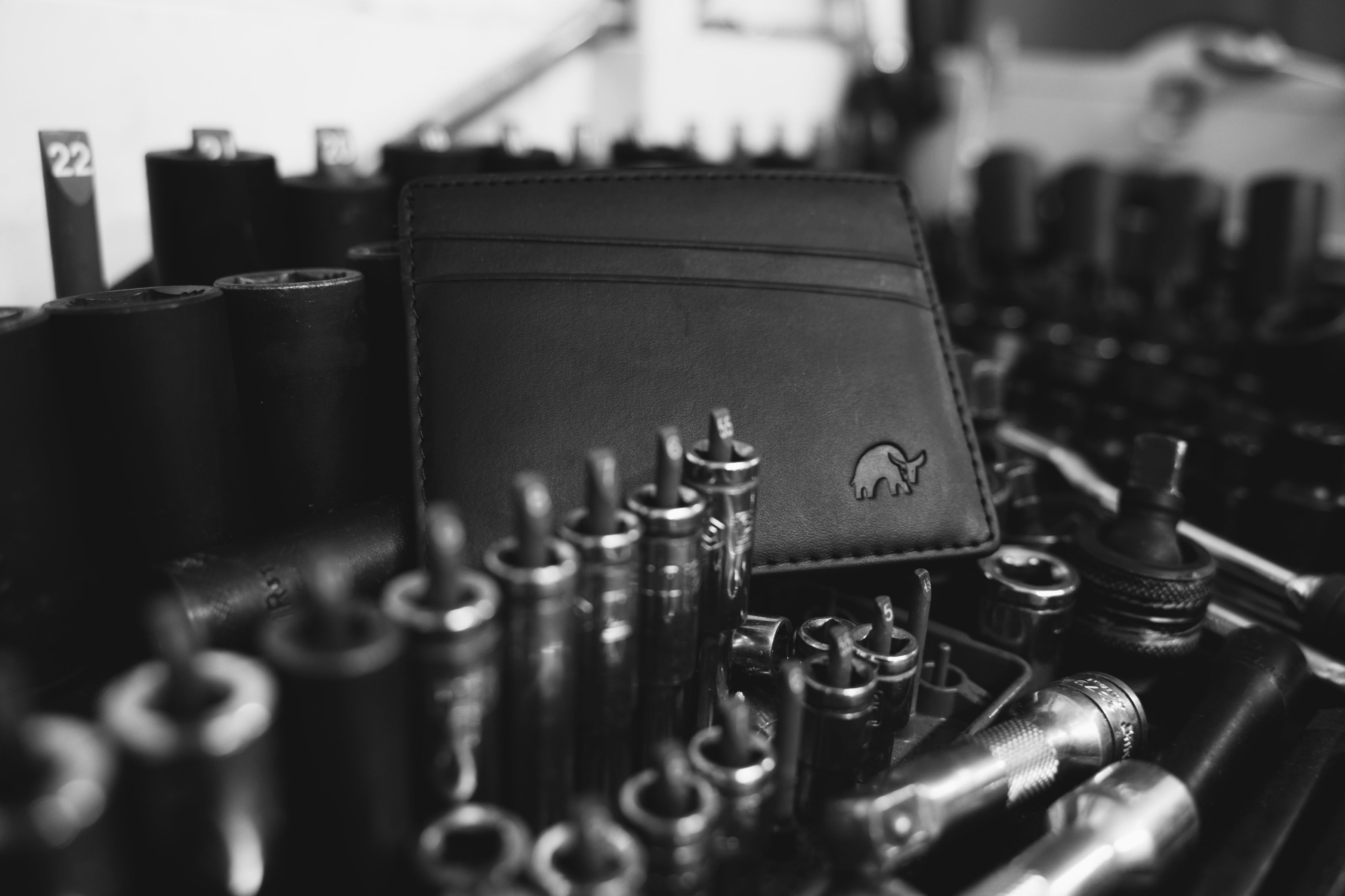 Black leather wallet with embossed elephant logo among socket bits and tools, visible tool labels '22' and '5'.