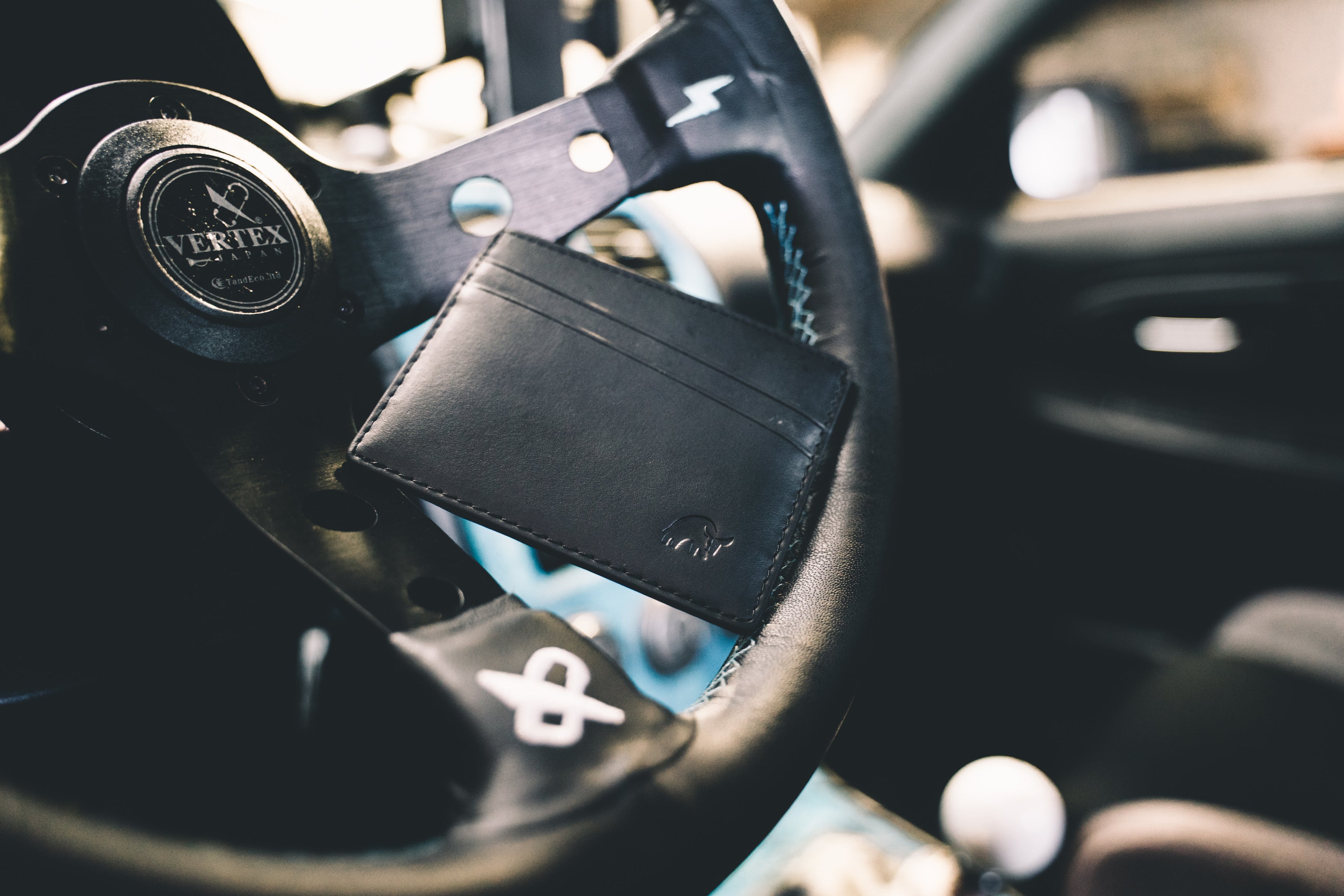 A leather card holder placed on a steering wheel in a car interior.