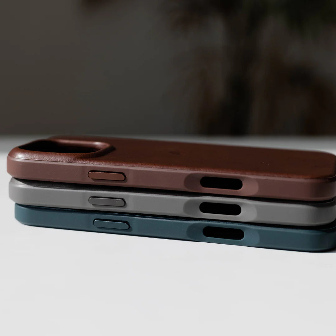 Three stacked smartphone cases (brown leather top, gray middle, dark teal bottom) showing side buttons and port cutouts.