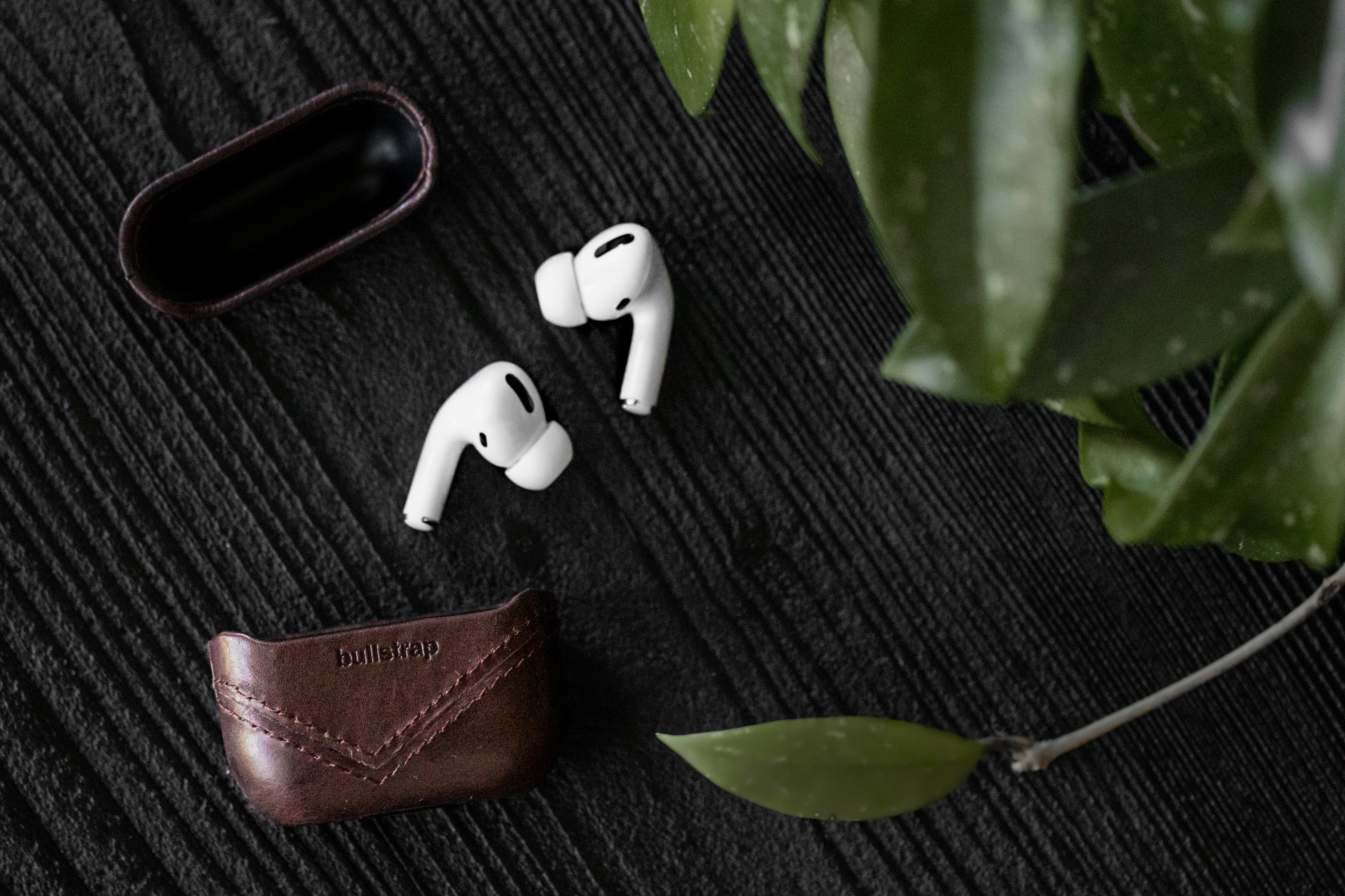 AirPods with Bullstrap leather case on a textured surface