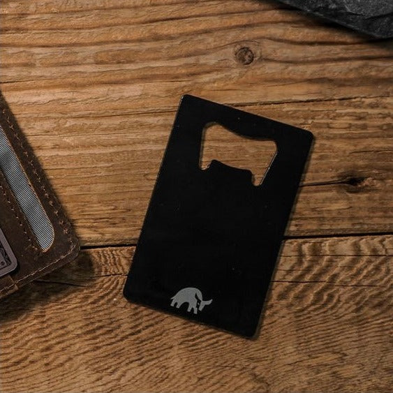 Black bottle opener card with a bull logo on a wooden surface