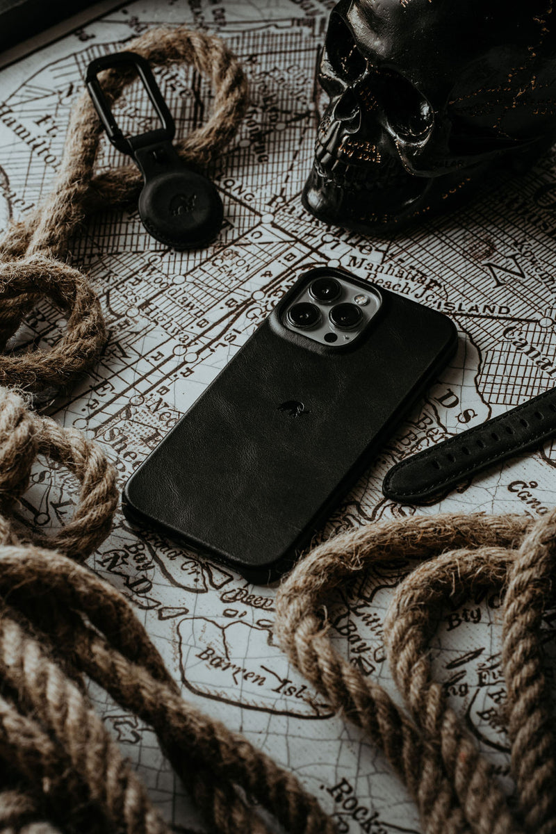Black leather iPhone on vintage map showing Manhattan Beach ISLAND, with rope and a black skull nearby