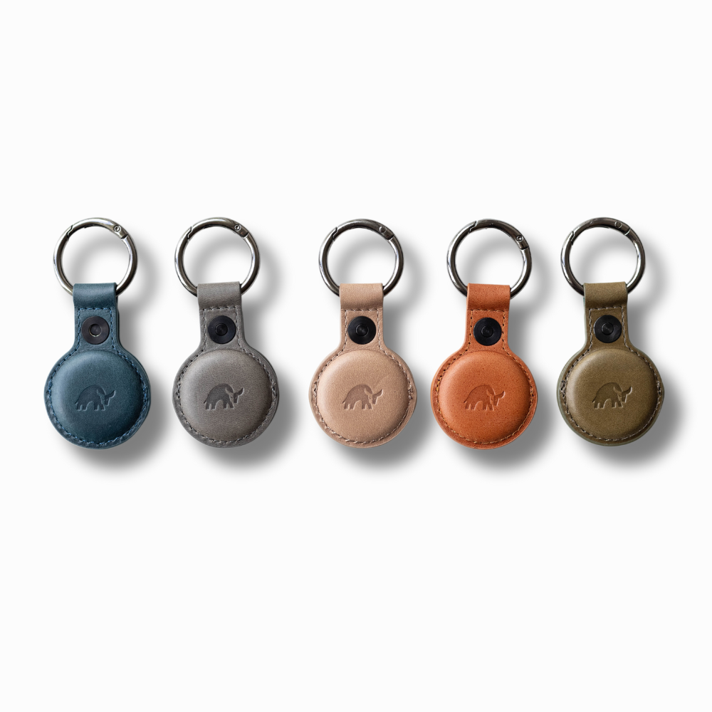 Five BullTag AirTag holders in various colors: blue, gray, tan, orange, and green.