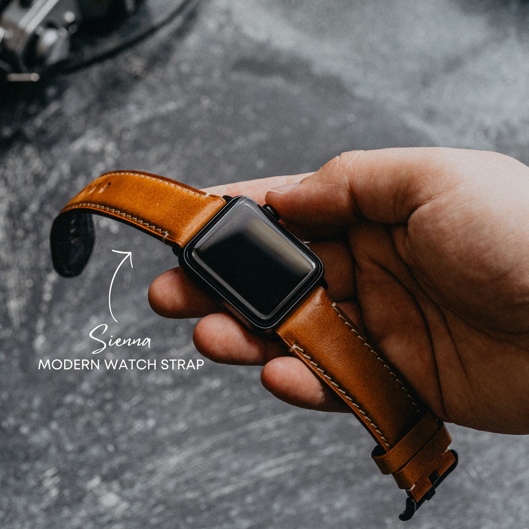 Hand holding a smartwatch with a brown leather strap labeled Sienna MODERN WATCH STRAP.