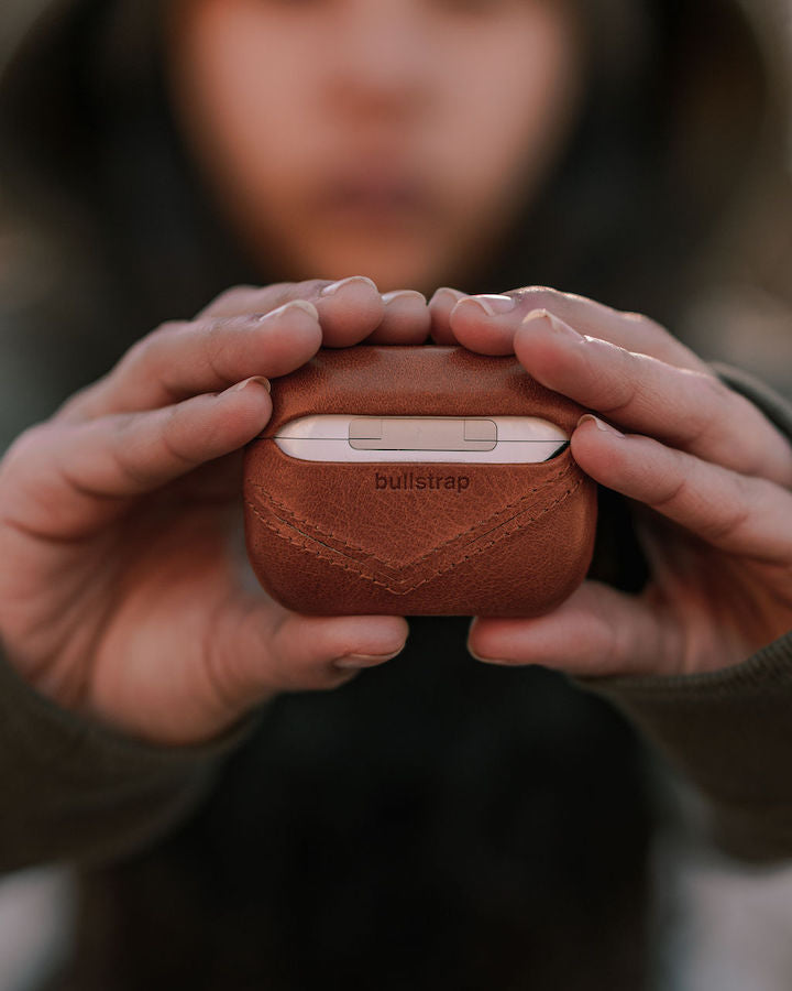 A person holding a Bullstrap AirPods case with the logo visible.