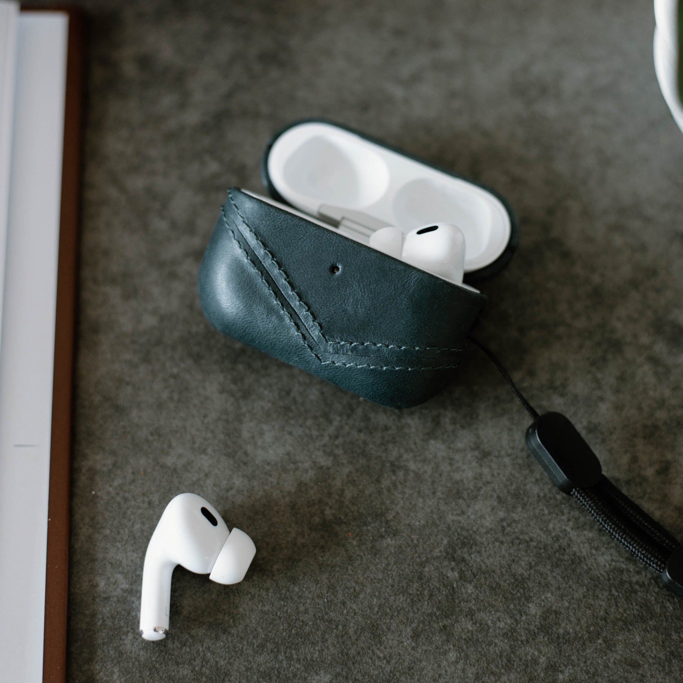 Leather AirPods case in ocean color with AirPods inside and outside the case