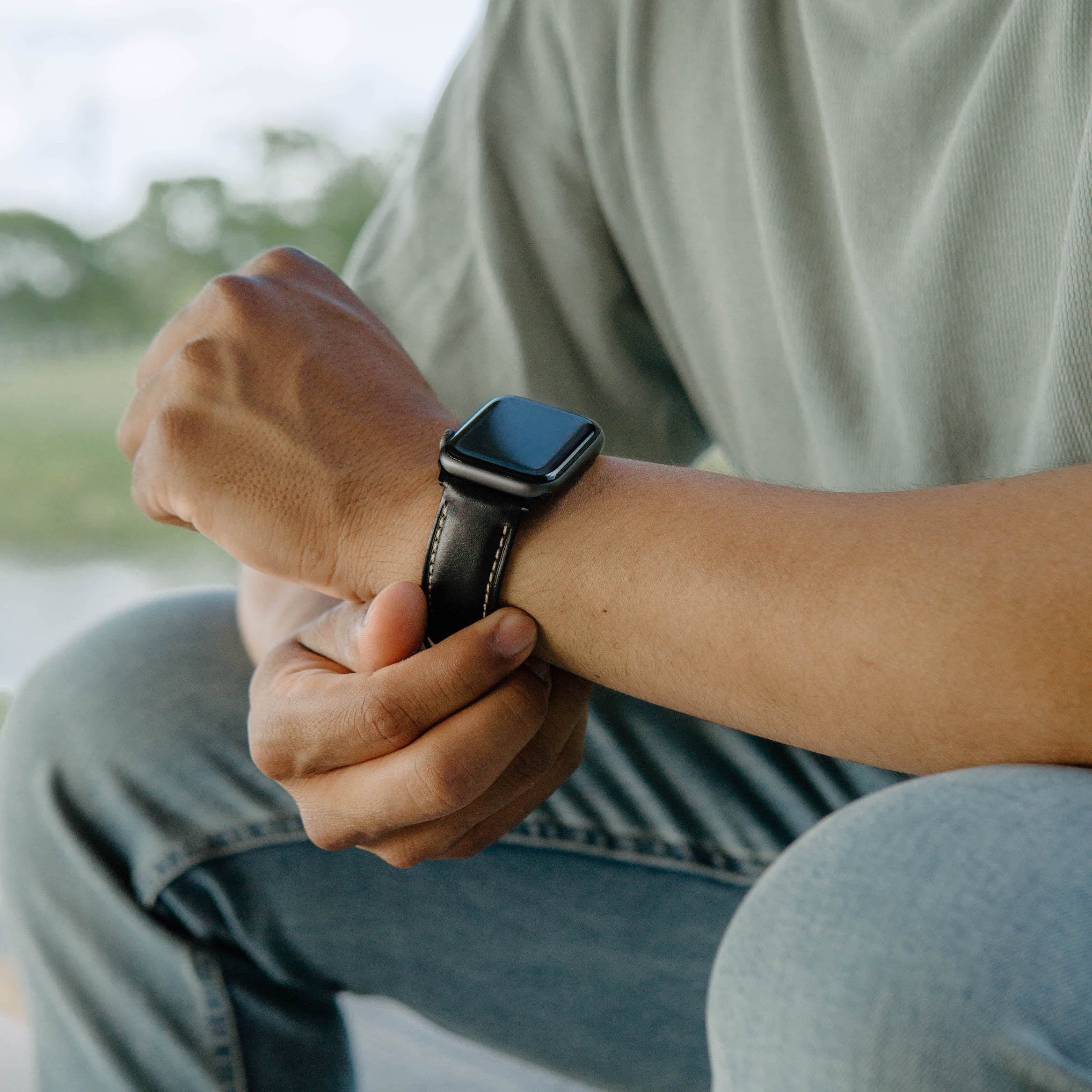 A person wearing a black leather Apple Watch strap on their wrist.