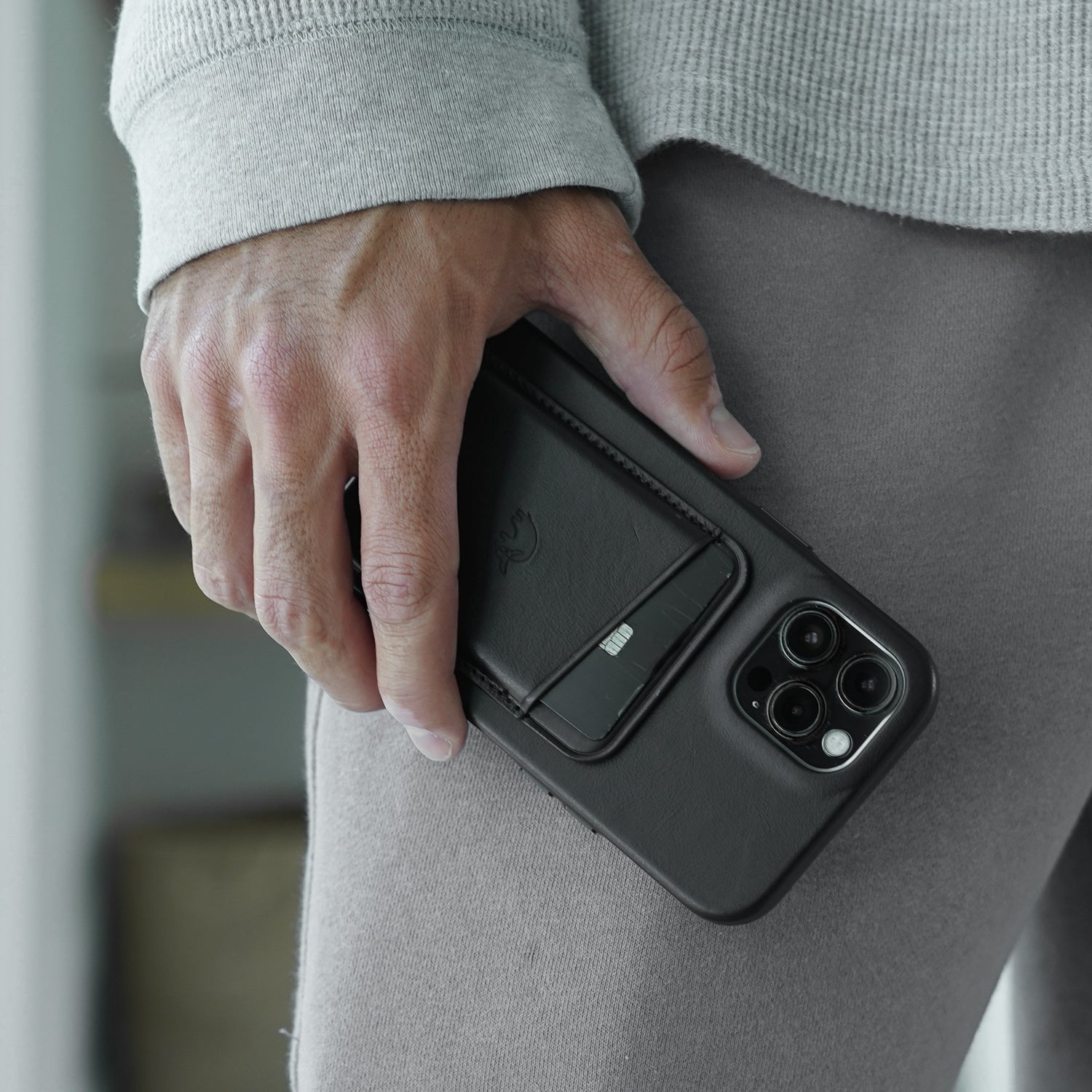 Hand holding phone with attached black leather magnetic wallet and exposed card slot