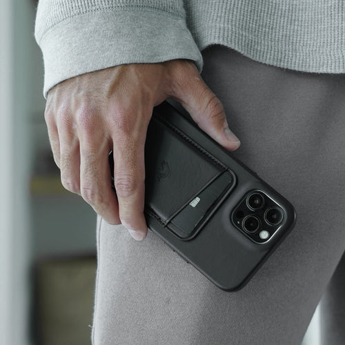 Hand holding phone with attached black leather magnetic wallet and exposed card slot