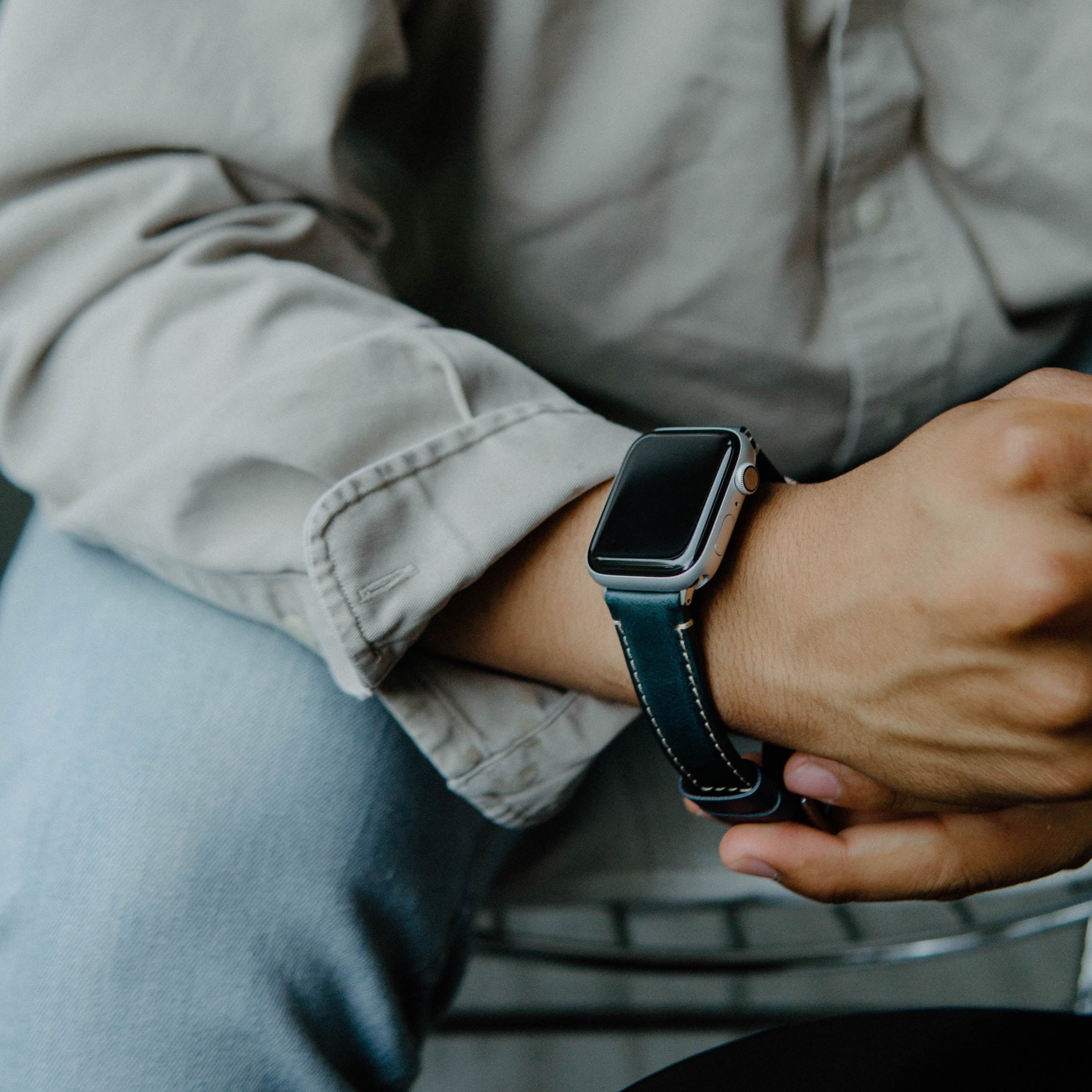 A person wearing a leather Apple Watch strap in ocean color on their wrist.