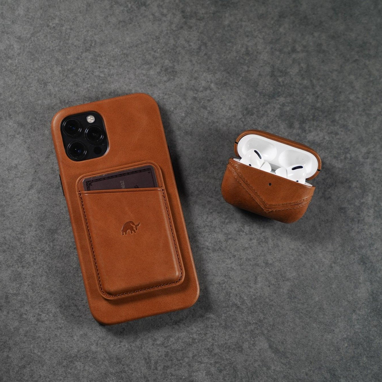 Brown leather AirPods case next to a phone case with a card slot.