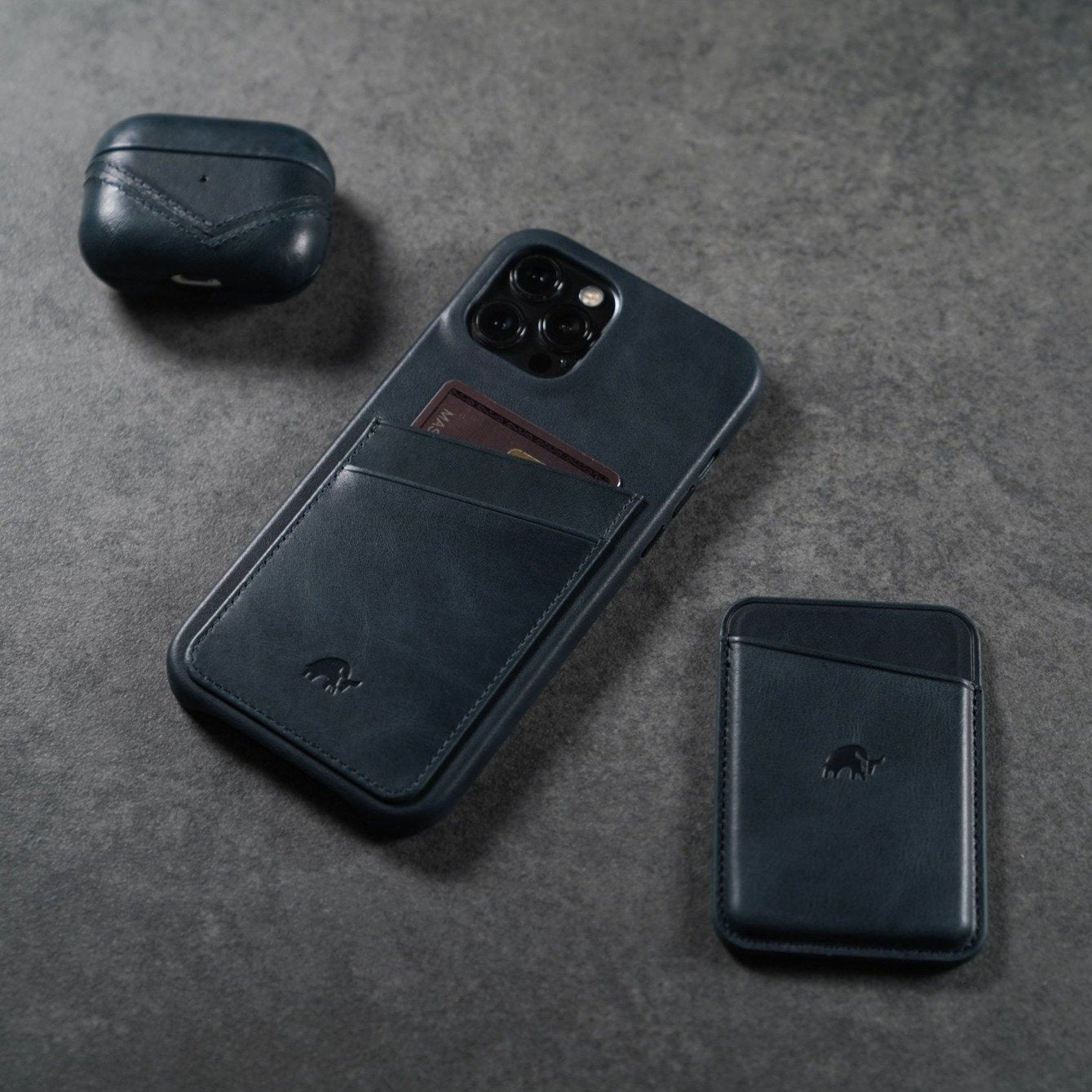 A leather AirPods case in ocean color, alongside a phone case and cardholder.
