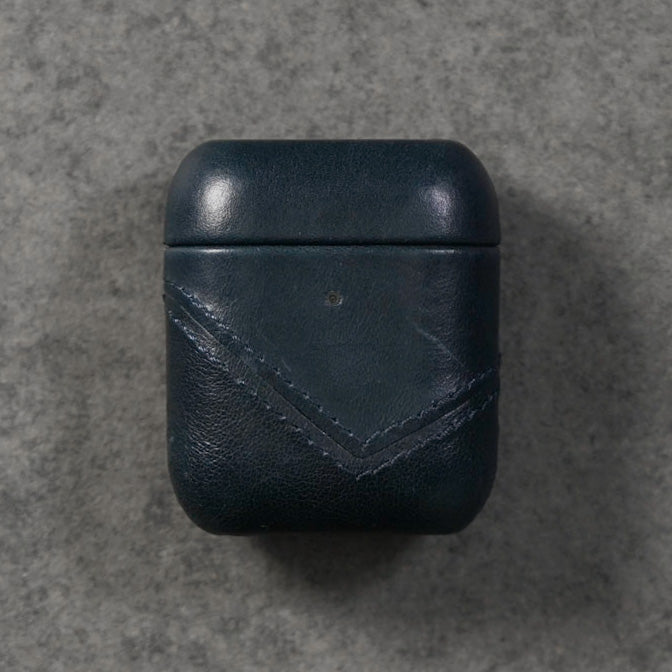 Top view of a dark blue leather AirPods case with a stitched design.