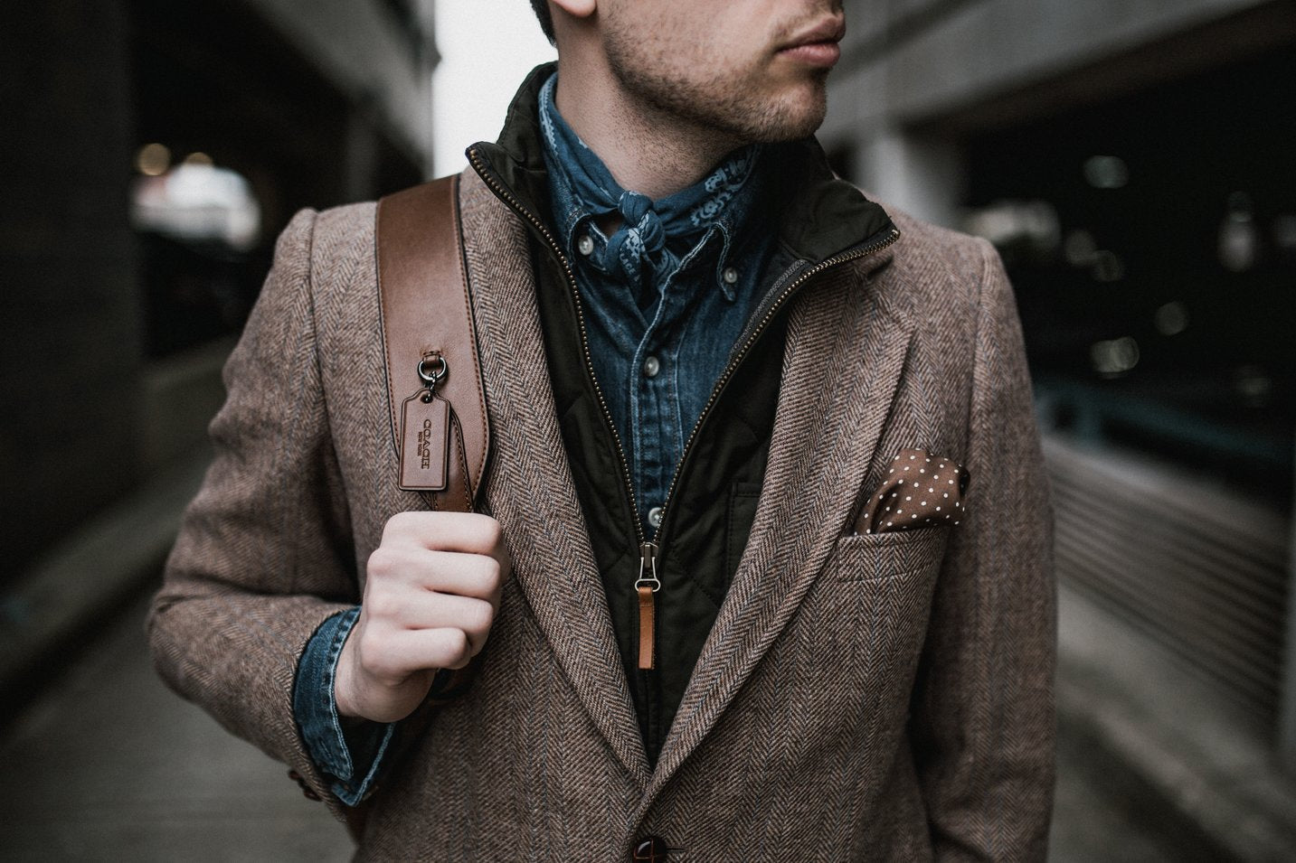 Man in a business casual outfit with a pocket square, bandana, and leather backpack
