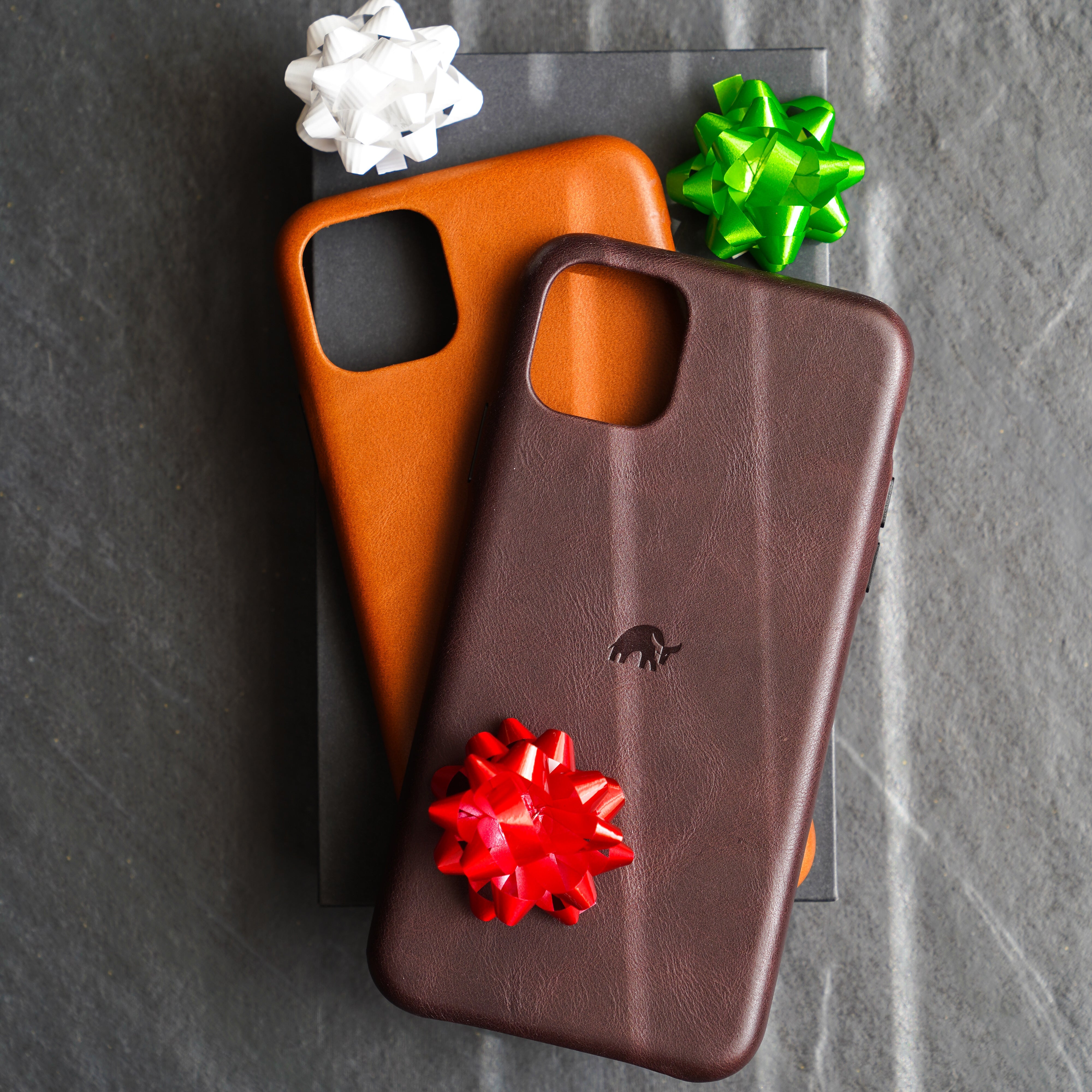 Two iPhone cases with decorative bows on top of a box