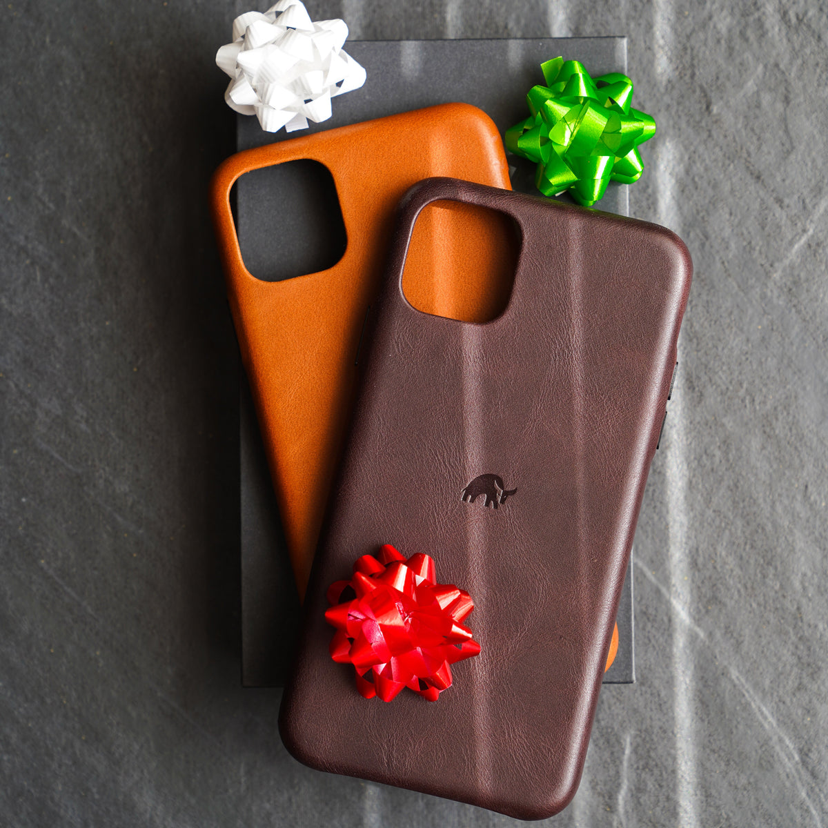 Two iPhone cases with decorative bows on top of a box