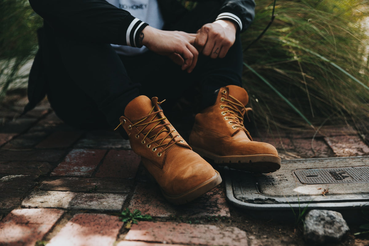 Man sitting on the dirty ground showing off his leather lace-up boots