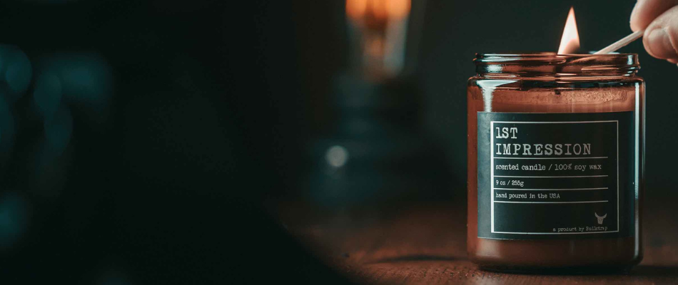 A lit candle labeled '1ST IMPRESSION' on a wooden table
