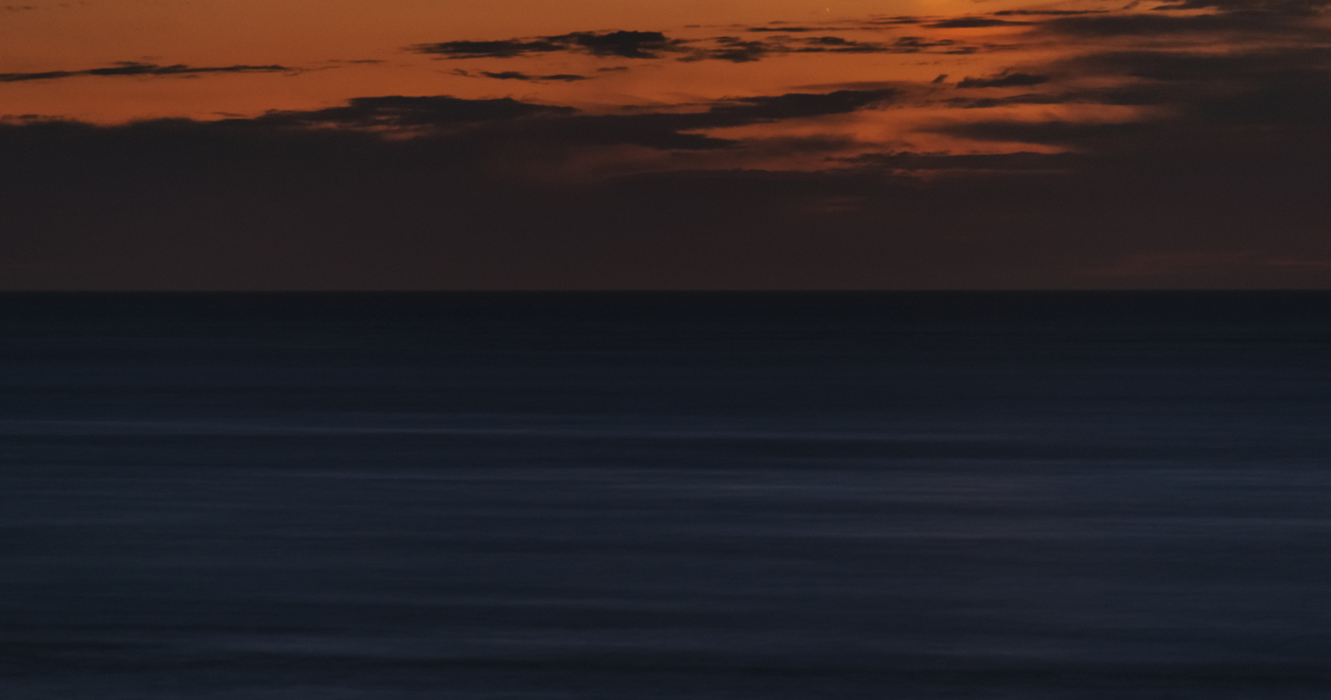 A sunset over the ocean with clouds and waves