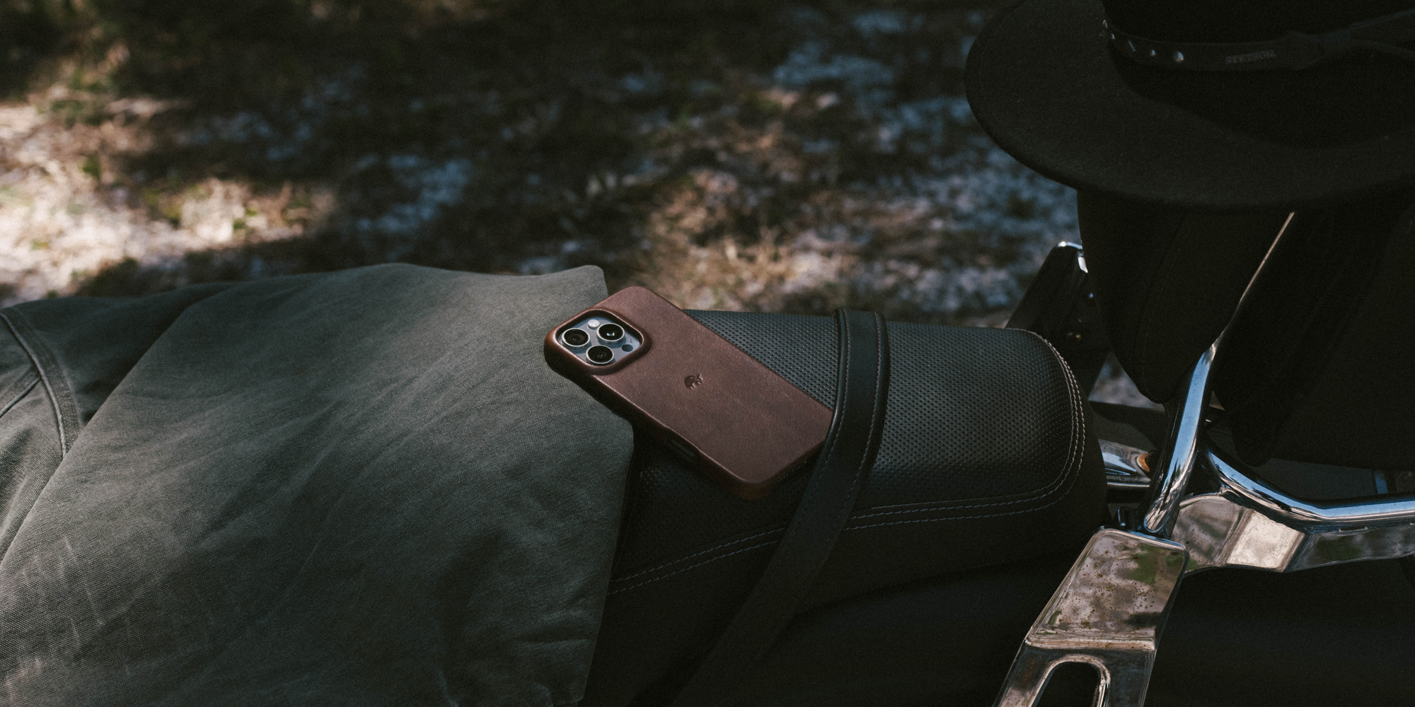 A brown leather phone case on a surface with coffee beans scattered around.