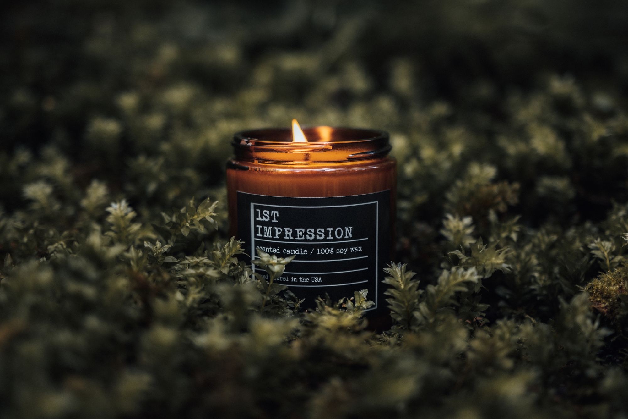 A lit candle labeled '1ST IMPRESSION' in a natural setting.
